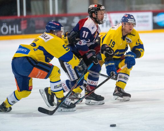 Gelingt es dem EHC Seewen die Siegesserie in Arosa fortzusetzen und den Leaderthron zu verteidigen. I Im Bild Jonas Fries im Sandwich von zwei Arosern. Bild Erhard Gick